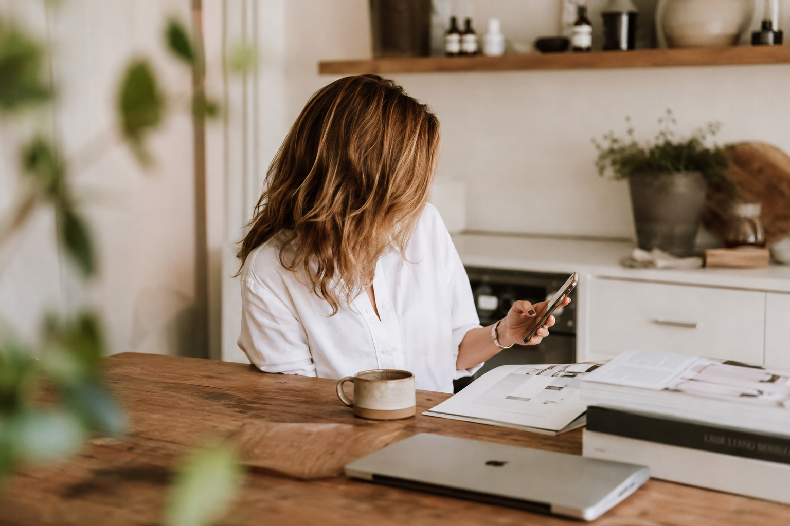 A med-spa owner glancing at her phone over morning coffee